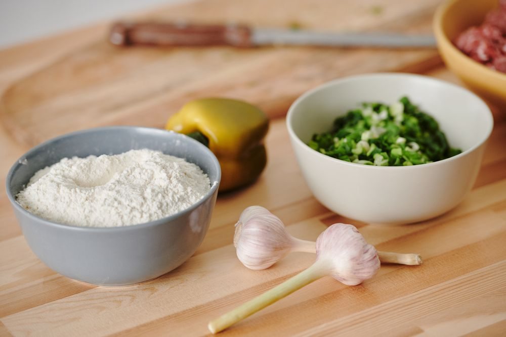 Ingredientes tradicionales de despensa con legumbres, ajos y hierbas sobre mesa de madera